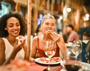 Two women eating bruschetta for Italian dinner.