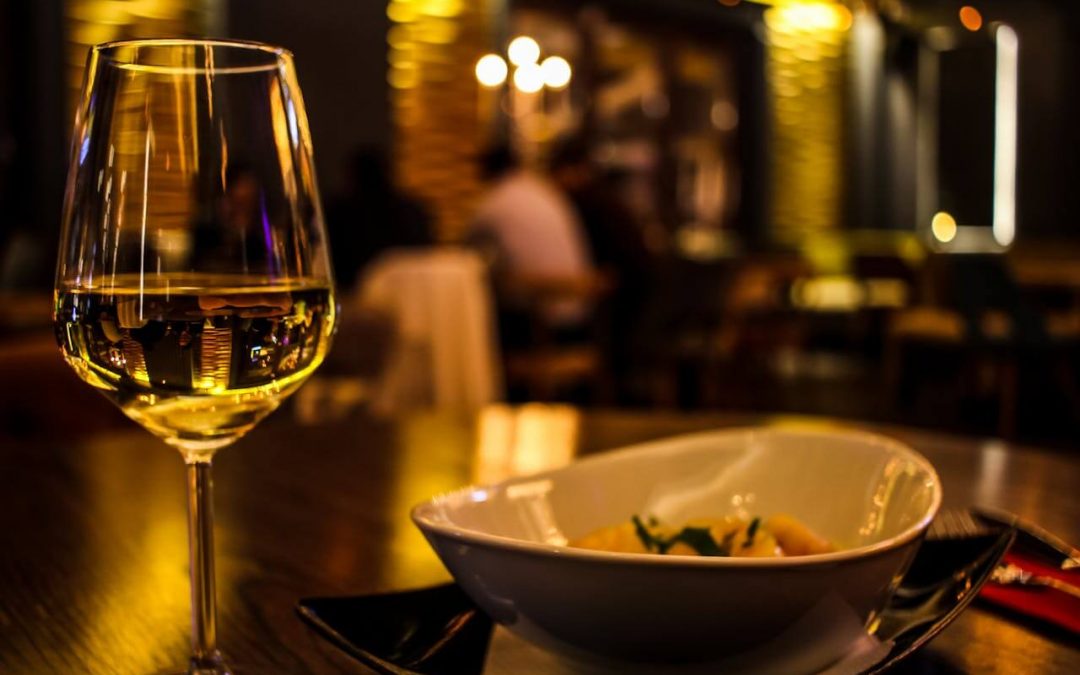 White wine beside a bowl of pasta