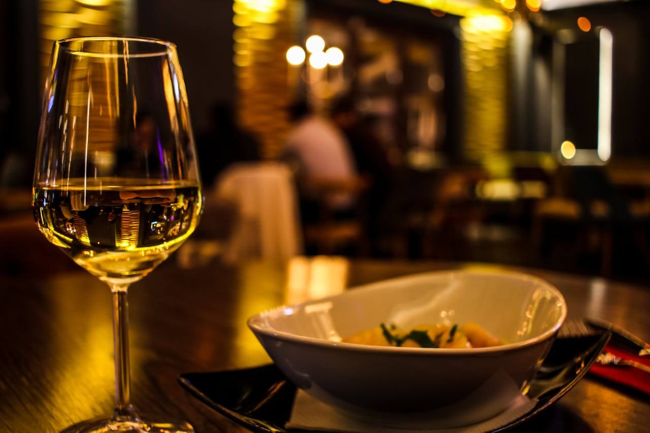 White wine beside a bowl of pasta